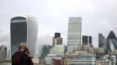 A woman takes a photograph in front of the skyline of the City of London, Britain January 24, 2016. The City of London financial district is home to a variety of banks and financial instiutions. REUTERS/Neil Hall