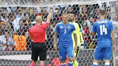 Slovakia defender Martin Skrtel is shown a yellow card by referee Szymon Marciniak after conceding a penalty. Carl Recine / Reuters