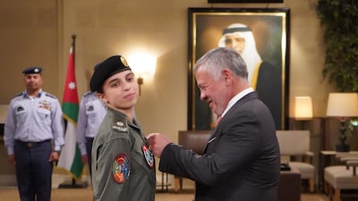 King Abdullah II presents Princess Salma bint Abdullah with her wings after completing her pilot training. AFP