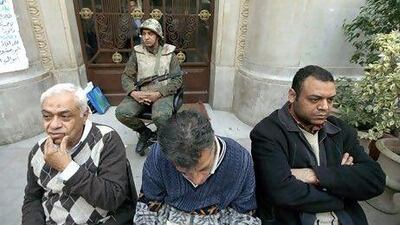 Investors sit by a soldier guarding the entrance to Egypt's stock exchange.