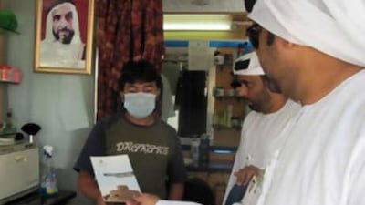 The municipality workers Ahmed al Dhaheri, right, and Obaid al Mazidi tell Teb Kantishil, from Bangladesh, about the Day Without Citations programme.