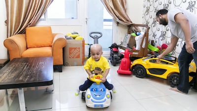 Toddler Aarev Shetty, 2, rides his toy car at home with his father, Sushant. Reem Mohammed / The National