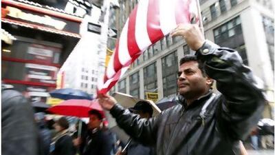A man uses an American flag to shelter himself from the rain during the 'Today, I Am A Muslim, Too' rally in New York City on Sunday, held to protest at the targeting of American Muslims and Arabs.