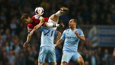Arsenal's Mathieu Flamini, top, challenges Manchester City's David Silva, No 21, and Pablo Zabaleta during their Premier League match at The Emirates Stadium in London on March 29, 2014. Eddie Keogh / Reuters