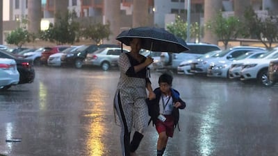 Families trot through the downpour in Dubai. Leslie Pableo for The National