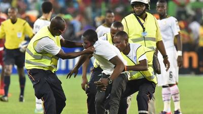 Security officers evacuate a supporter who made his way onto the pitch during the 2015 African Cup of Nations semi-final football match between Equatorial Guinea and Ghana in Malabo, on February 5, 2015. Play was halted eight minutes from time in the Africa Cup of Nations semi-final between hosts Equatorial Guinea and Ghana when missiles were thrown on the pitch. AFP PHOTO / ISSOUF SANOGO