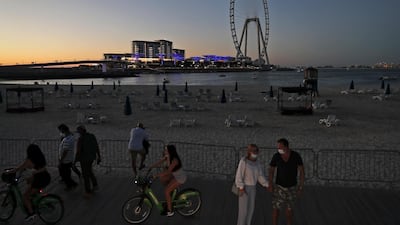 Tourists and residents enjoy the sunset at Jumeirah Beach Residence, with the Dubai Eye on Bluewaters Island in the background
