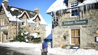 A woman walks past a Tea Shop with icicles hanging from the roof. Getty Images