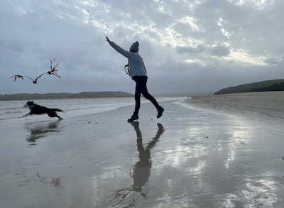 A woman plays with her dog on Padstow Beach. PA