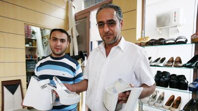 Saif, left, and Mohammed Ahmed show off some of the extra-tall shoes they make for brides. Fatima Al Marzooqi / The National