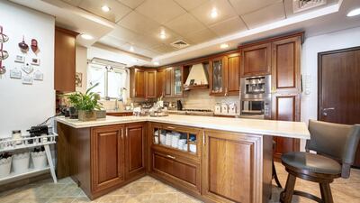 The kitchen comes with wooden cabinets and marble countertops. Courtesy LuxuryProperty.com