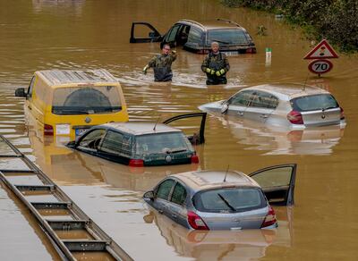 People check for victims in flooded cars on a road in Erftstadt, Germany. AP