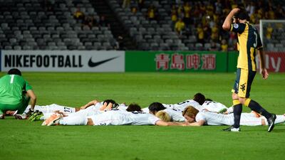 Sanfrecce Hiroshima players lay on the ground after scoring against Central Coast Mariners in their Asian Champions League match in Gosford, Australia, on March 11, 2014. Sanfrecce's players formed the figure "3.11", a tribute to the victims of the March 11, 2011, twin disasters that struck Japan. William West / AFP