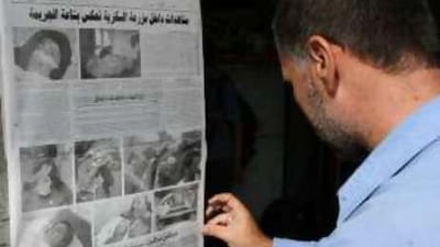 A man displays a newspaper article about the attack in Syria that killed eight people near the Iraq border.