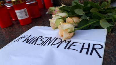 Candles and flowers are seen placed at the Brothers Grimm monument for the victims of a shooting in Hanau, near Frankfurt, Germany. The sign reads "We are more". Reuters
