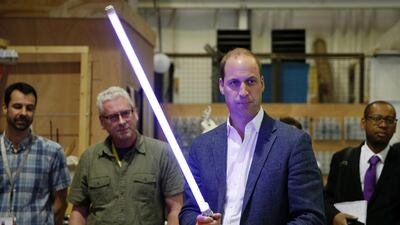 The Duke of Cambridge, Prince William holds a light sabre during a visit to the Star Wars film set on April 19, 2016. Courtesy Adrian Dennis/AFP