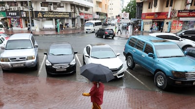 A resident takes cover during a recent bout of rain in Dubai. Chris Whiteoak / The National