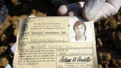 A Filipino forensic expert shows the identification card of Daniel Tiamzon, one of the journalists killed in the Mindanao massacre last year.