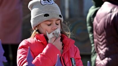 A girl kisses her pet rodent outside a five-storey residential building, part of which collapsed after a shelling. AFP