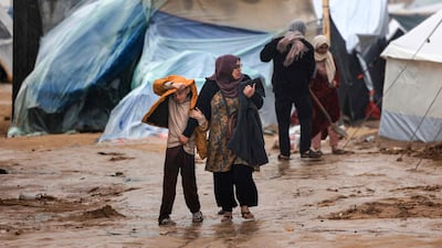 Palestinians walk in the rain at a camp for displaced people in Rafah, southern Gaza Strip. AFP