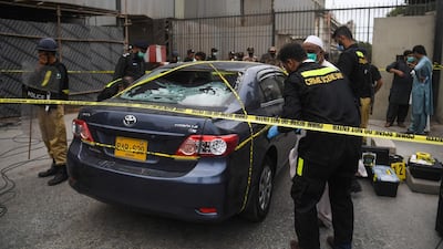 Policemen guard as members of Crime Scene Unit investigate around a car used by alleged gunmen at the main entrance of the Pakistan Stock Exchange building in Karachi. Gunmen attacked the Pakistan Stock Exchange in Karachi on June 29, with four of the assailants killed, police said. AFP