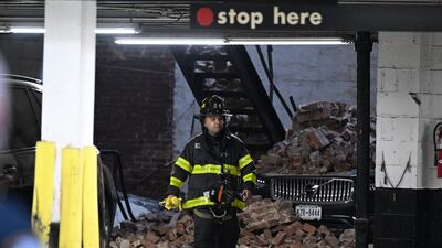 A member of the New York Fire Department walks past a car covered in rubble. AFP