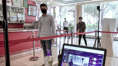 Workers pass thermal scanners before presenting identification needed to enter Al Raha Mall, May 18. Victor Besa / The National
