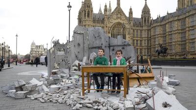 Two children whose school was destroyed in Aleppo pose in a mocked-up bombed classroom, set up at the Houses of Parliament, London, by the charity Save the Children ahead of a donor fundraising conference for Syrian refugees. Justin Tallis / AFP