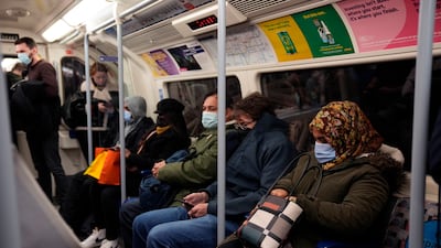 People wear masks on board a London Underground train, where enforcement has been limited. AP