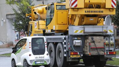 An Elbee vehicle driven by a factory worker passes a truck-mounted crane during a test drive in Lostice. David W Cerny / Reuters
