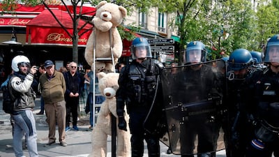 French riot police officers stand next to giant teddy bears, during the May Day demonstration, in Paris. AFP