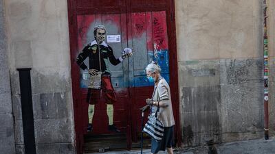 An elderly woman wearing a face mask to protect against the coronavirus walks past a painting named 'to be or not to be' by artist TVBOY and depicting Spanish government's top virus expert Fernando Simon in Madrid, Spain. AP Photo