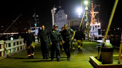 Local fire officials along with search and rescue teams walk off the dock. AP