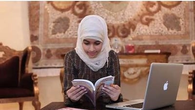 Fatima Rahma, 11, spends some time during Ramadan reading books and browsing on the computer. Her mother hopes to shield her from overindulgence.