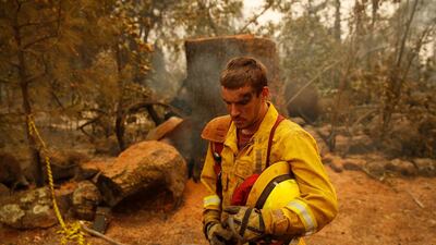 Shawn Slack rests after felling trees burned in the Camp Fire in Paradise. AP Photo