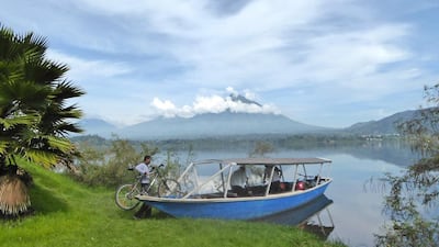 A cyclist loads his bike onto a boat to be taken across Lake Ruhondo in Rwanda, in the foothills of the Volcanoes National Park, home to mountain gorillas. Will Hide