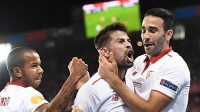 Coke, centre, celebrates with teammates Adil Rami, right, and Mariano Ferreira after scoring to put Sevilla 2-1 ahead. Jean-Christophe Bott / EPA