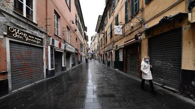 A person wearing a face mask walks in downtown past closed shops in Genoa. EPA