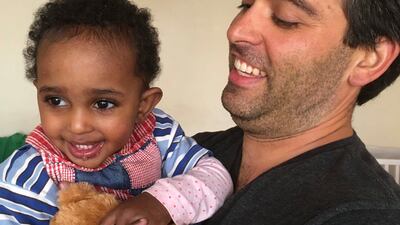 In this photo provided by Ben Pascal, he is seen holding his daughter, Naomi Pascal, with her Teddy at an orphanage in Ethiopia in June 2016. Naomi lost Teddy in Glacier National Park in October 2020, but a park ranger picked it up and had it on the dash in his pickup truck when a family friend spotted it in September 2021. The bear is back with Naomi at her home in Jackson, Wyoming. (Ben Pascal via AP)