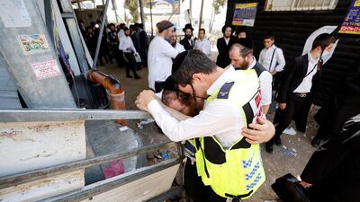 Emergency workers support each other at the site where 45 people were crushed to death at a religious festival at Mount Meron, Israel. Reuters