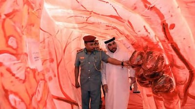 Ayman Kamel Ibrahim, a security officer with the Health Authority-Abu Dhabi, and Sami Zayed al Monzeui, a community police officer, walks through a replica colon at Abu Dhabi Health Authority.