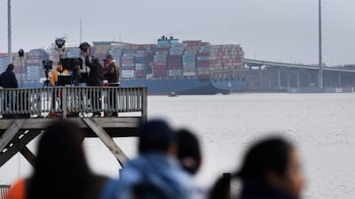 News crews and residents gather along the shoreline. Rescuers pulled two people from the Patapsco River but were searching for at least seven more. AFP