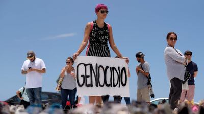 A woman holds a placard that reads in English "genocide" in front of hundreds of shoes that were displayed in memory of those killed by Hurricane Maria in front of the Puerto Rican Capitol, in San Juan. Ricardo Arduengo / AFP