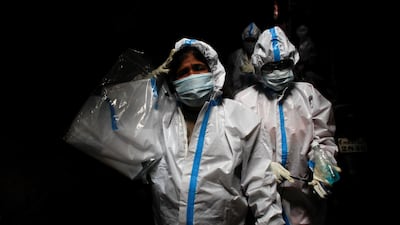 A health worker in personal protective equipment reacts as she and the rest of the team walk through an alley during a check up campaign for the coronavirus disease (Covid-19) at a slum area in Mumbai, India, August 3, 2020. Reuters