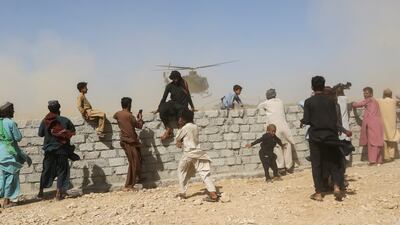 Residents gather as a rescue helicopter with medical supplies lands in a quake-hit Balochistan district, in south-west Pakistan. Reuters