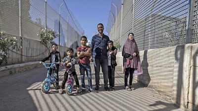 Palestinian Saadat Sabri Gharib (3-R) is pictured with family members between Israeli army barriers, that lead to his house which is an enclave at the heart of the Jewish settlement of Givon Hahadasha, north of Jerusalem, bordering the West Bank Palestinian village of Beit Ijza, on July 19 2022. - For years the family home stood amid swathes of farmland dotted with olive trees, but now it lies behind a yellow gate, controlled by Israeli soldiers, who also patrol a narrow bridge overlooking the eight-metre (26-foot) fence. The Gharib family has fought numerous legal battles in Israeli courts, in 2012 winning the right to around three percent of the land they claim. (Photo by MENAHEM KAHANA / AFP)