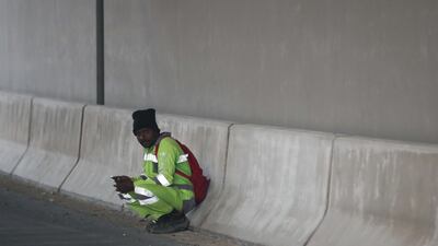 A worker takes cover from the elements along the E11 motorway.