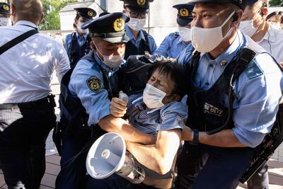 Police officers remove a protester from near the hotel where International Olympic Committee president Thomas Bach is staying in Tokyo. AFP