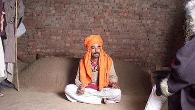 Safdar Ali sits in front of the grave in which he spent 41 hours. His faith healer told him the burial would stop his 'possession'.