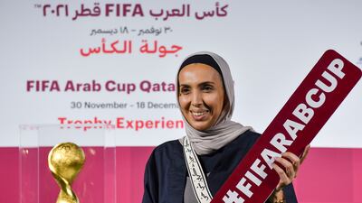 A woman poses next to the Fifa Arab Cup Trophy.